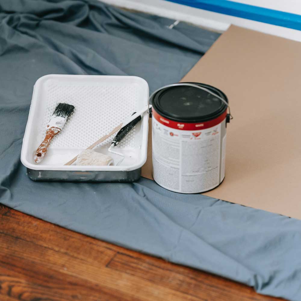 paint tray, brush and paint can on masked floor